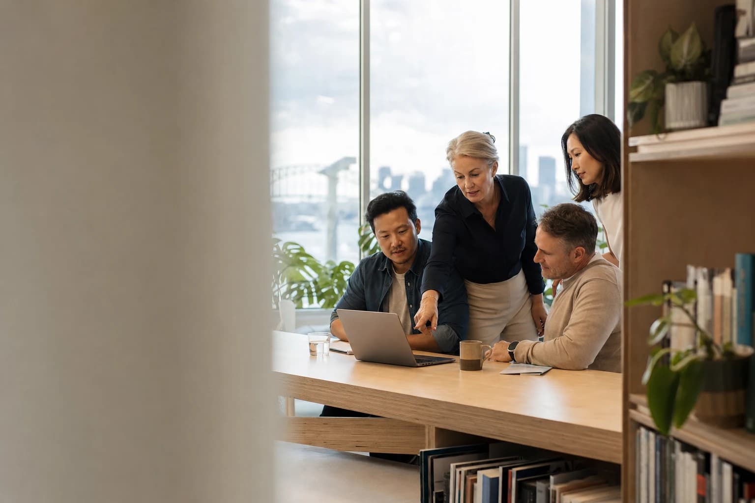 Senior business team gathered around a laptop in a Sydney office reviewing Copilot workflows